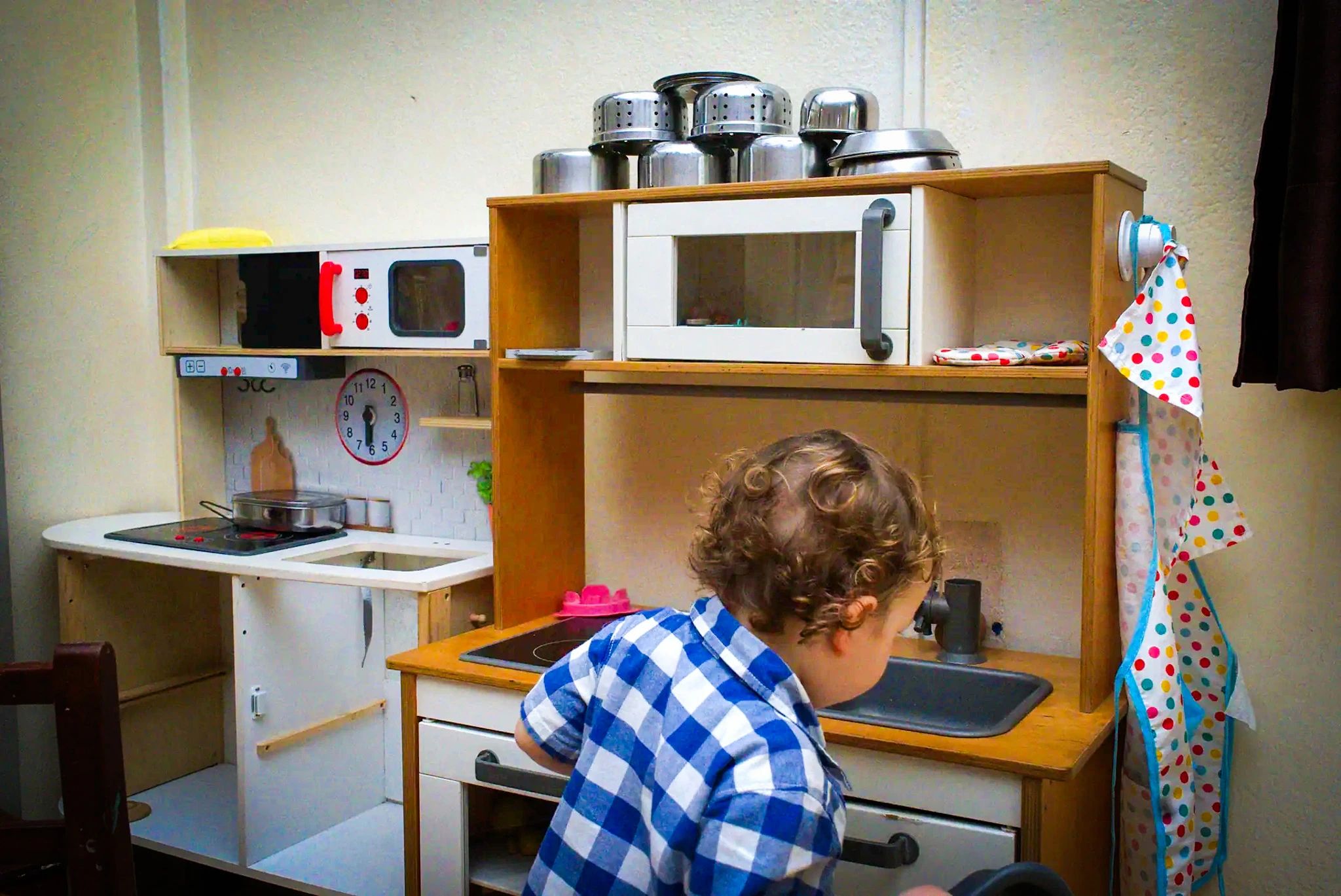 Un enfant, de dos, devant la cuisine en bois